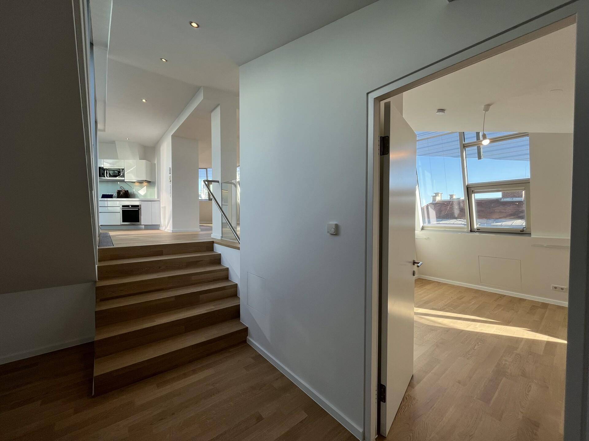 Heller Flur mit Holztreppe und Zugang zu weiteren Räumen der Wohnung.
