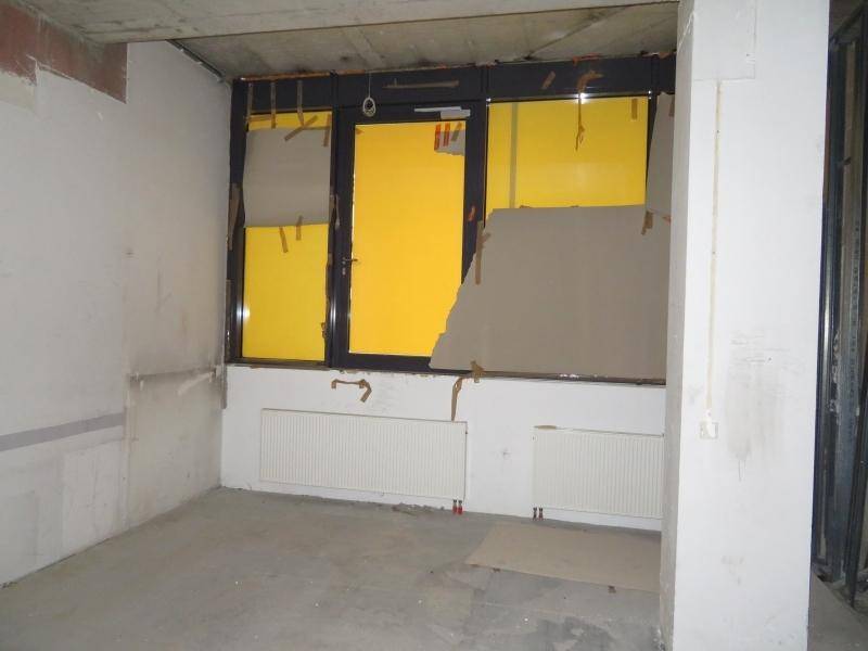 Unfertiger Raum mit rohem Beton an der Decke, Heizkörpern und provisorisch abgedeckten Fenstern.