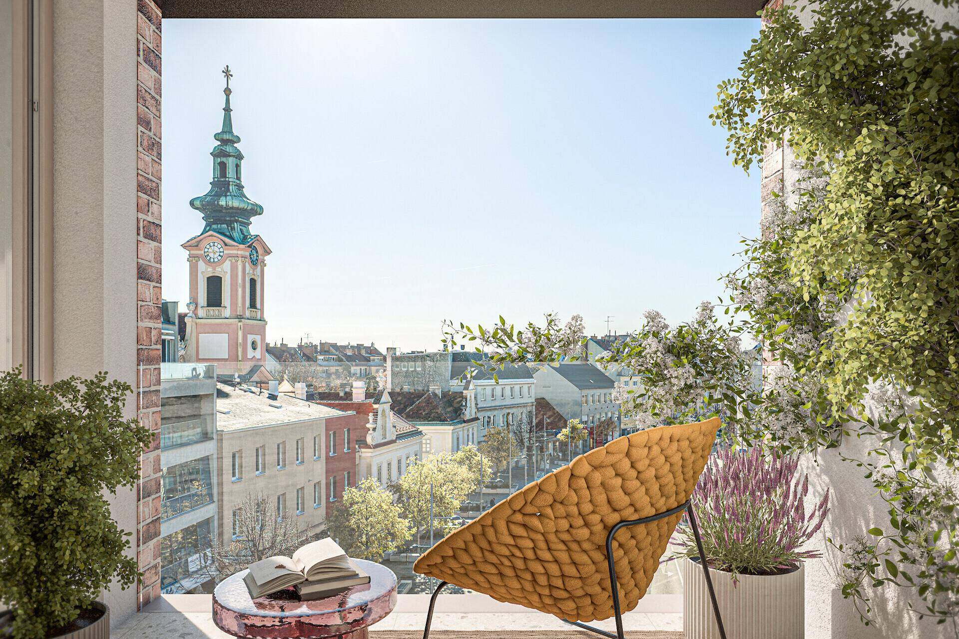 Blick von einem Balkon mit Pflanzen auf einen historischen Kirchturm und die Dächer der Stadt.
