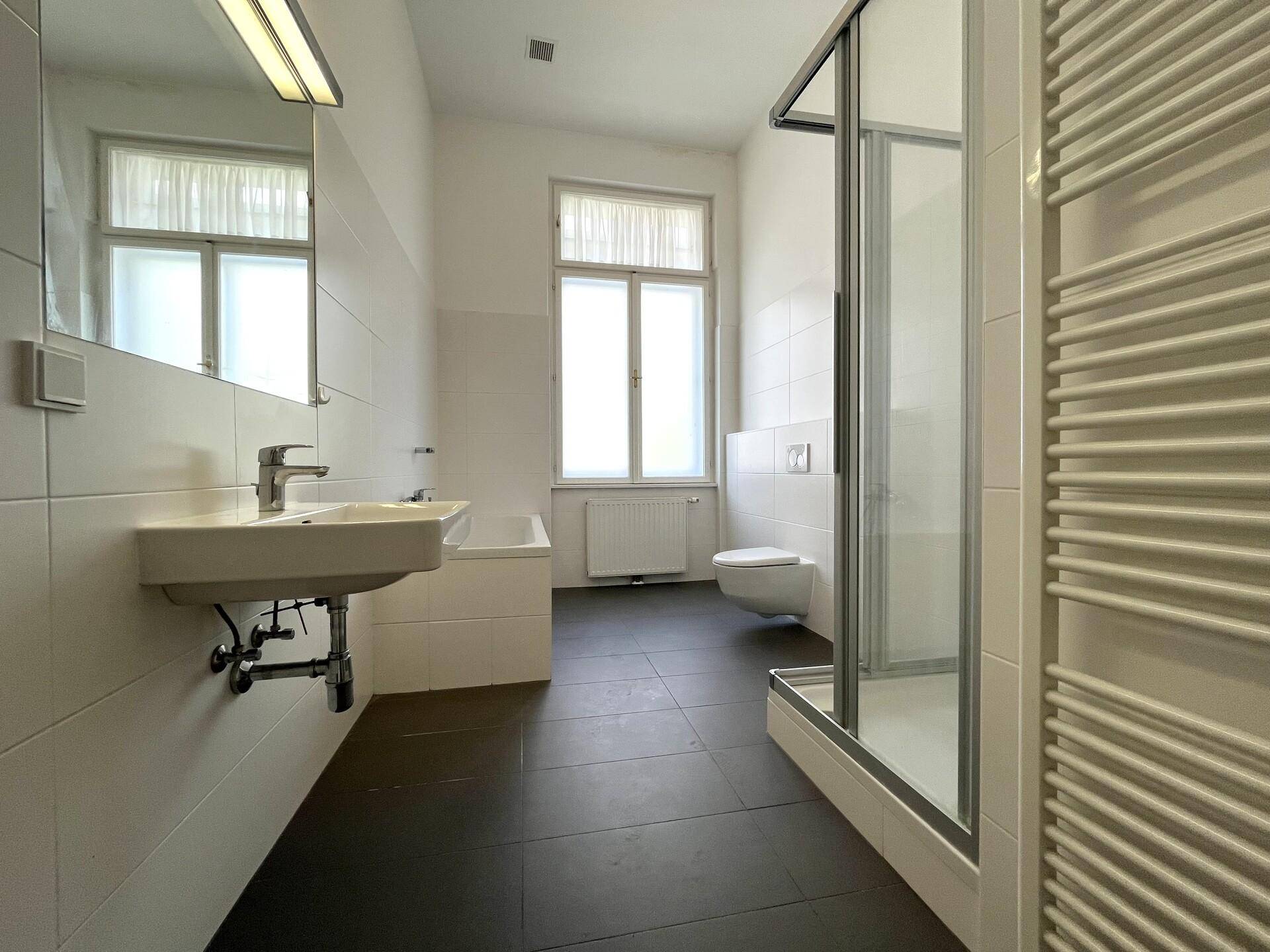 Modernes Badezimmer mit Badewanne, Duschkabine, wandhängendem WC und beheiztem Handtuchhalter.