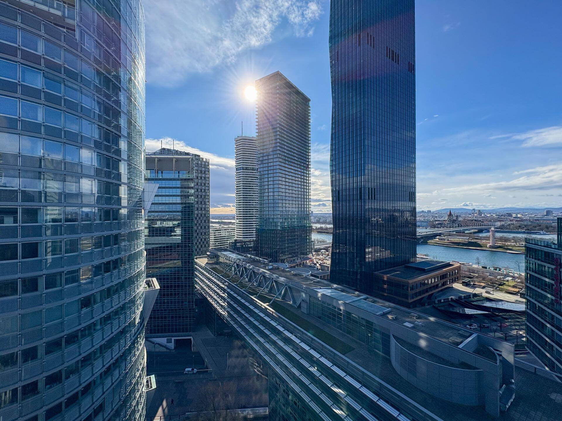 Beeindruckender Blick auf die moderne Skyline mit Hochhäusern, Fluss und Brücke unter strahlend blauem Himmel.