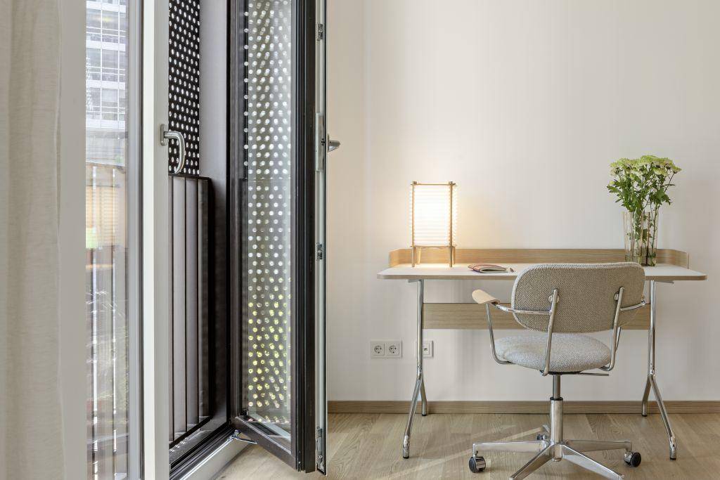 Heller Arbeitsbereich mit Schreibtisch und Stuhl, direkt am Fenster mit Zugang zum französischen Balkon.