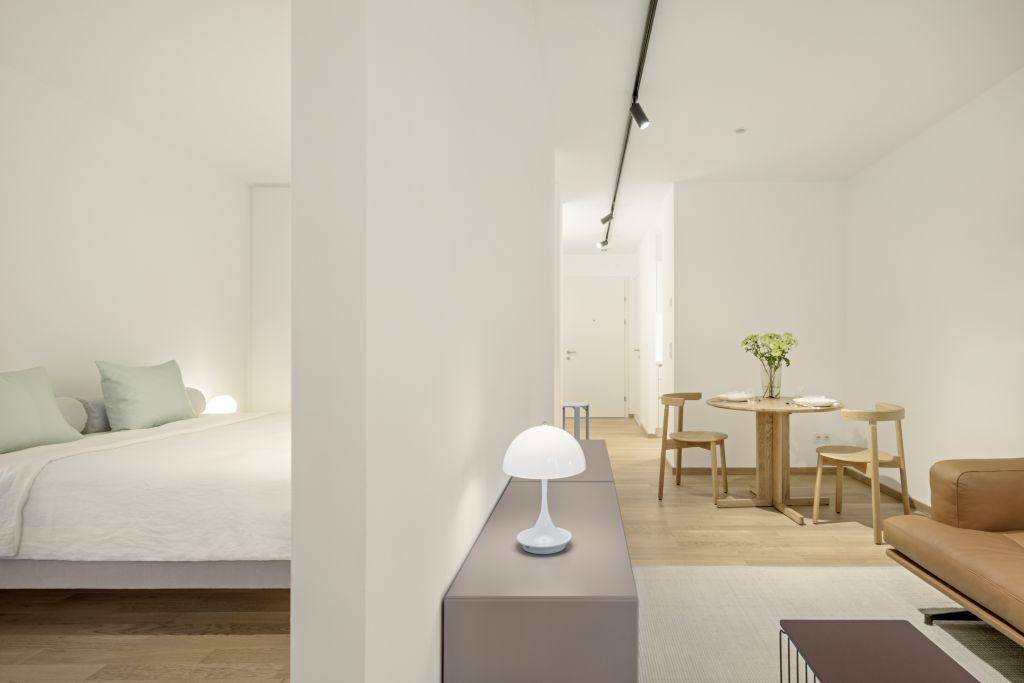 Offener Wohnbereich mit Schlafzimmer, Essbereich und Holzboden in hellem Design.
