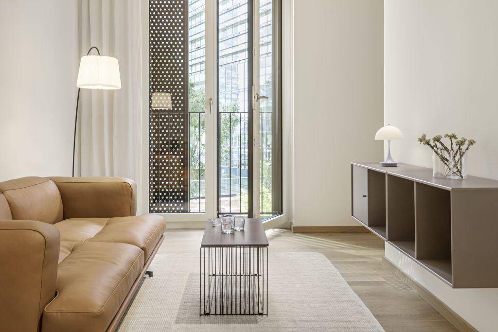 Helles Wohnzimmer mit modernem Sofa, Holzboden und Zugang zu einem französischen Balkon.