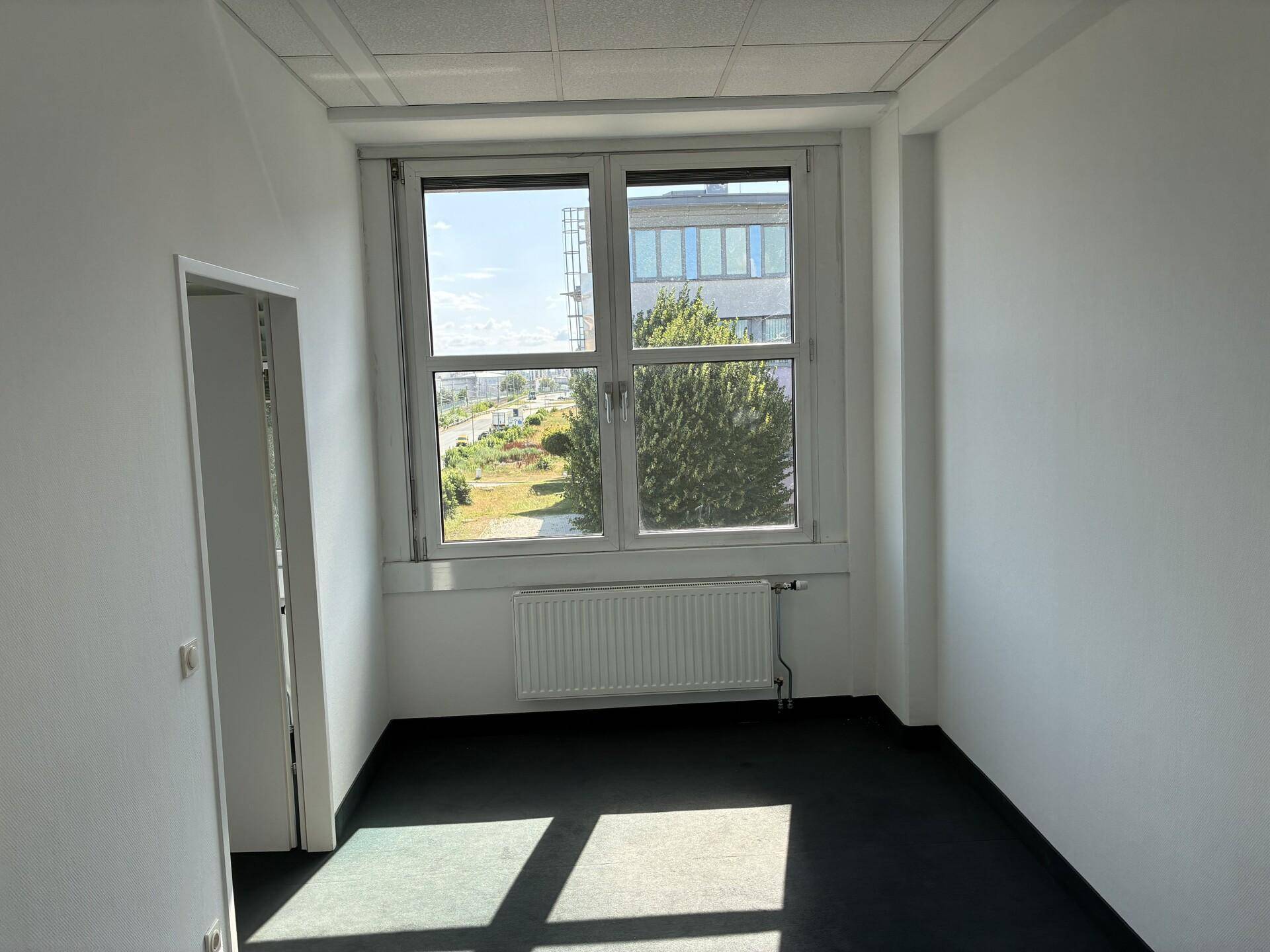 Kleinerer Büroraum mit einem großen Fenster, das einen Blick ins Grüne ermöglicht.