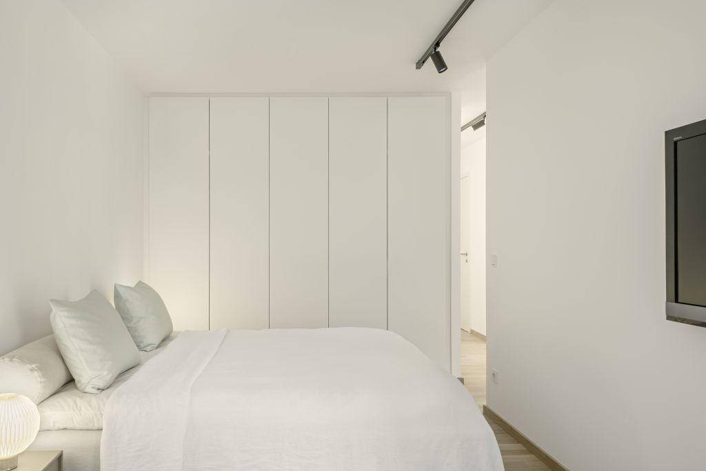 Modernes Schlafzimmer mit integrierten weißen Einbauschränken und minimalistischer Einrichtung.