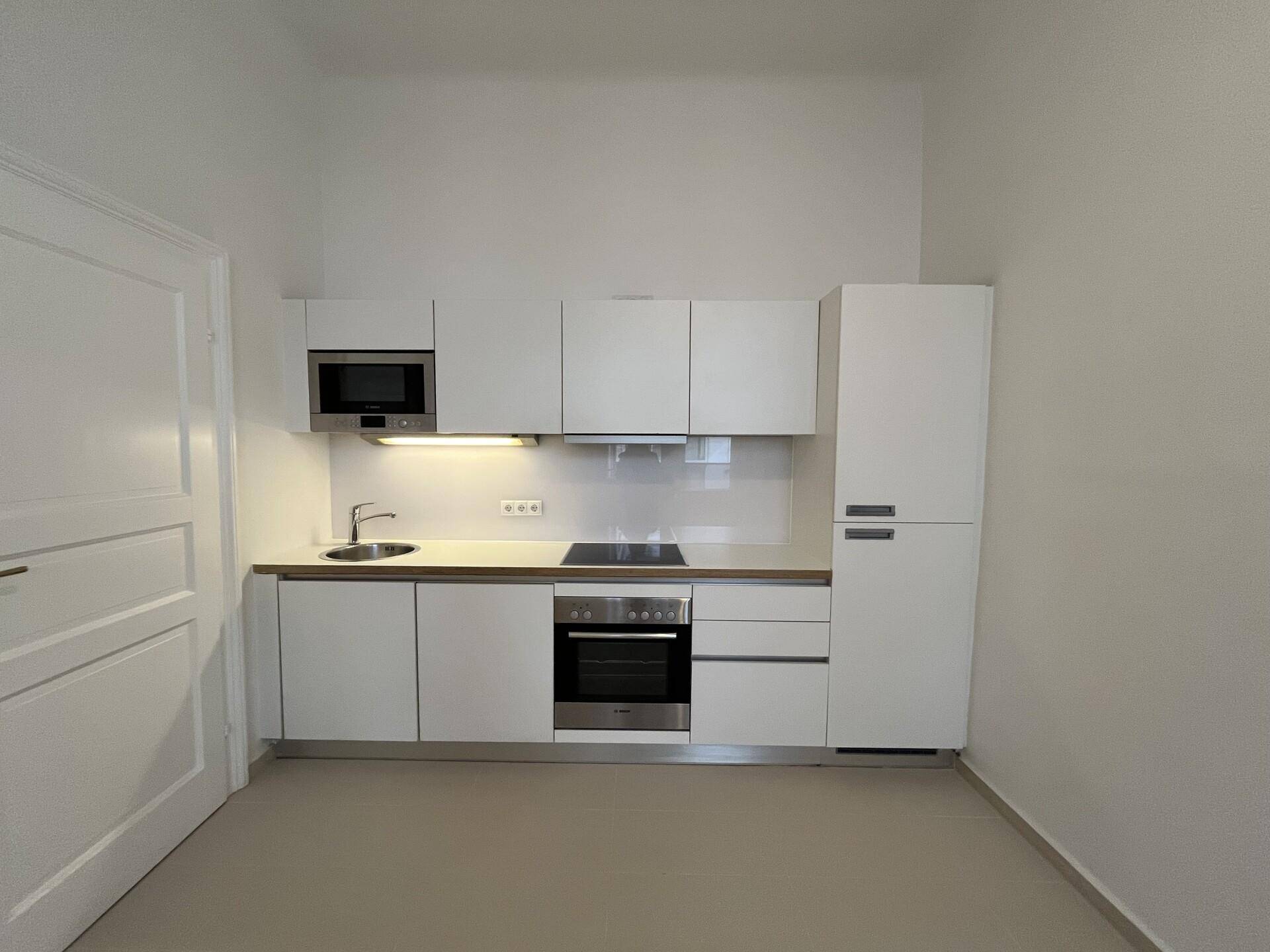 Moderne Einbauküche mit weißen Schränken und integrierten Geräten, funktional und platzsparend gestaltet.