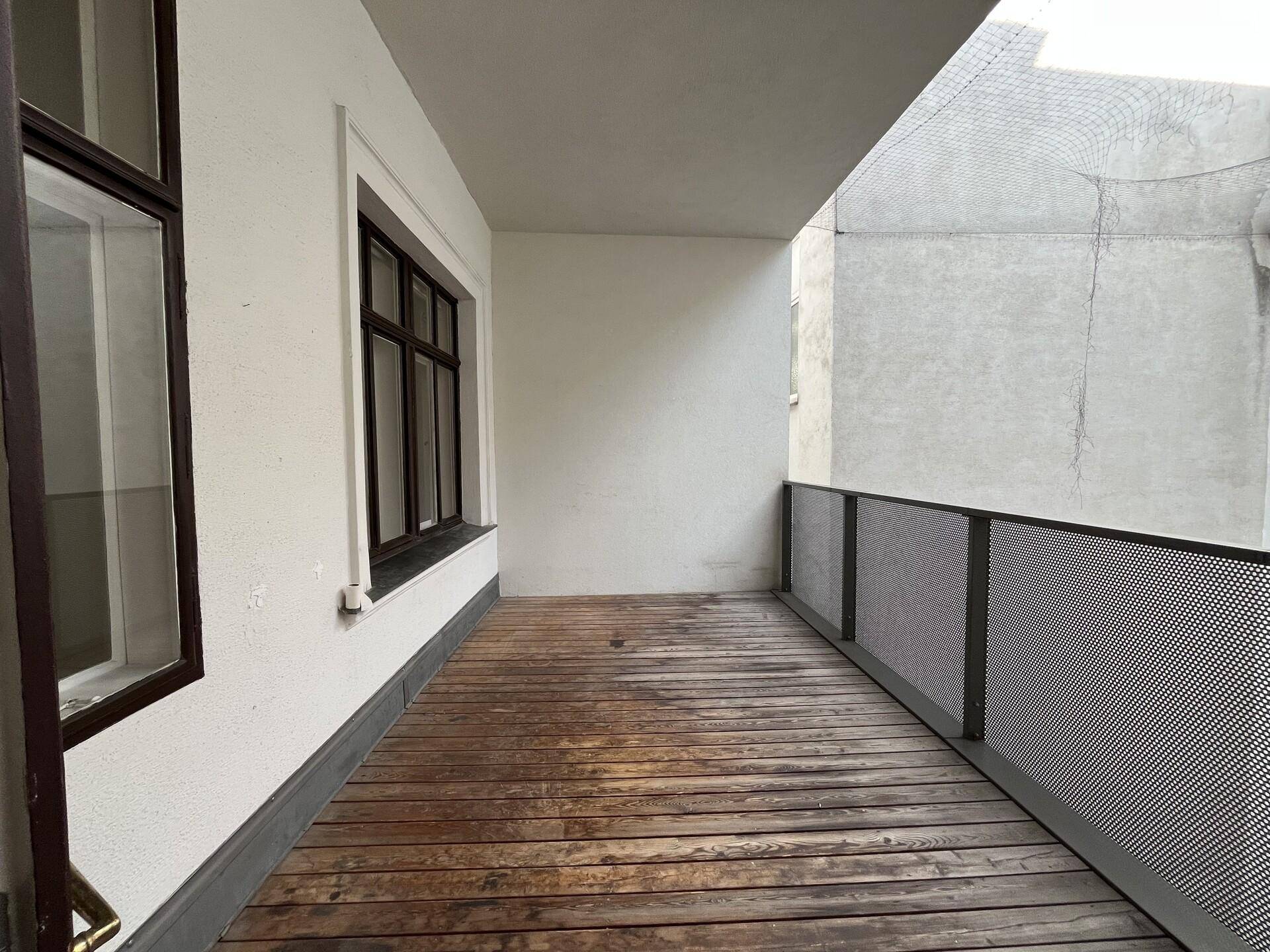 Langer Balkon mit Holzboden und modernem Metallgeländer, bietet einen privaten Außenbereich.