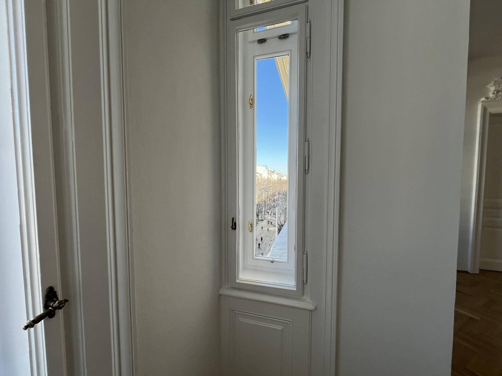 Hohes Fenster mit Blick auf die verschneite Straße, das viel Tageslicht hereinlässt.