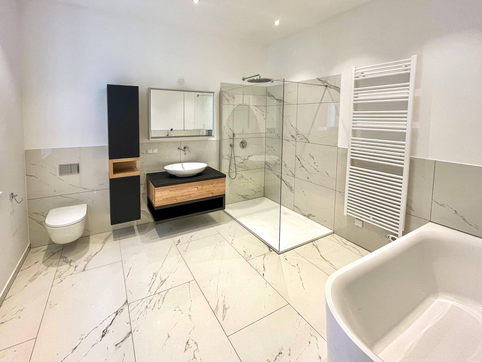 Modernes Badezimmer mit Marmorfliesen, begehbarer Dusche, freistehender Badewanne und Doppelwaschbecken.