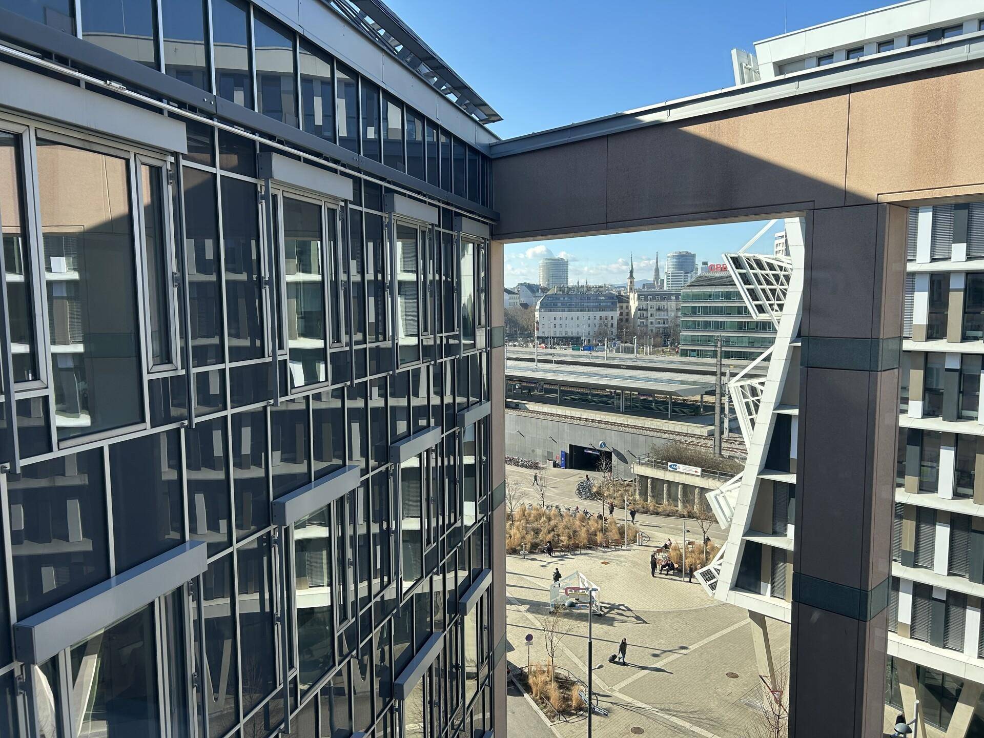 Blick aus dem Gebäude auf die Stadt, Bahngleise und umliegende moderne Architektur.