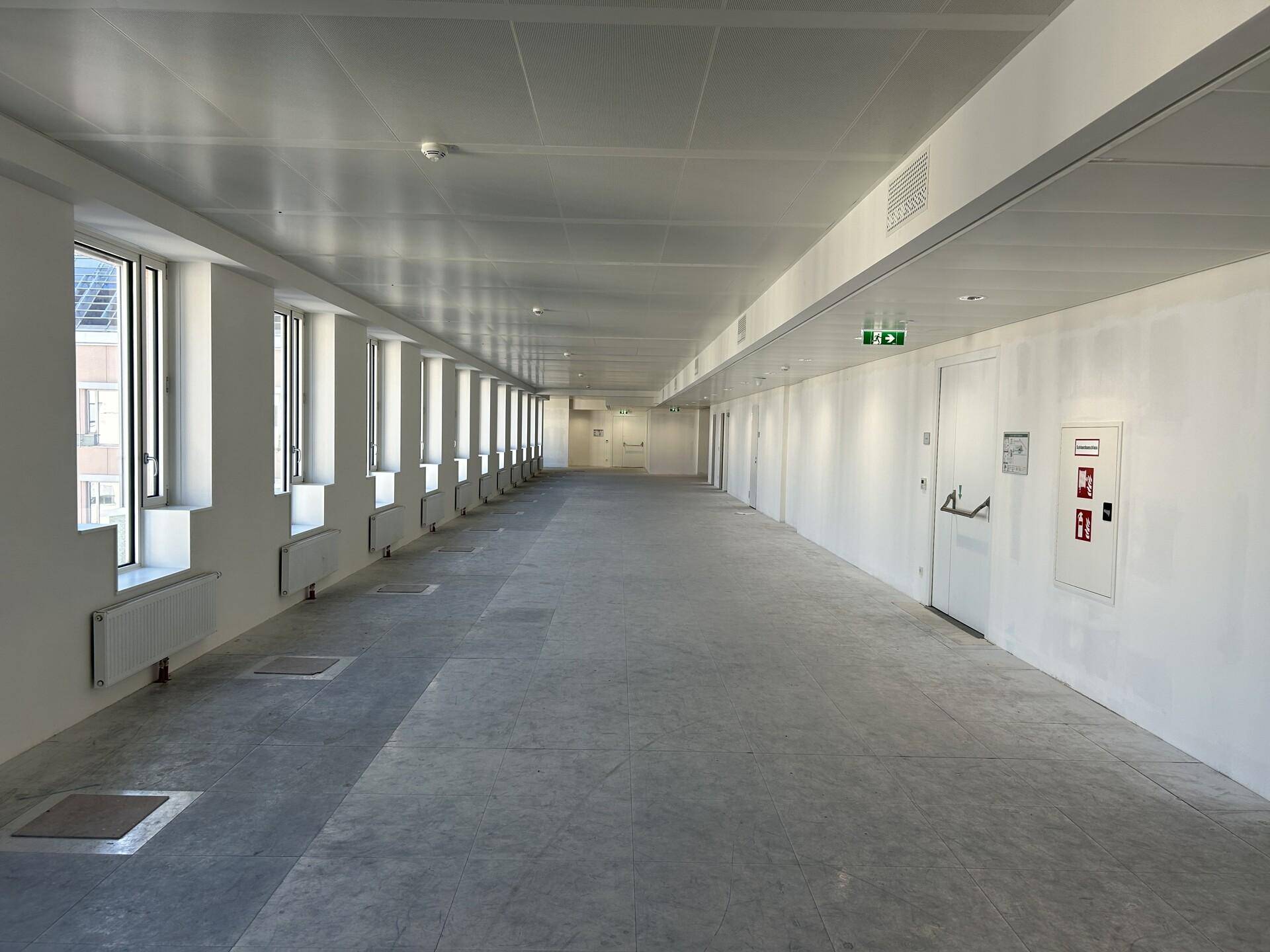 Geräumiger, unmöblierter Bürobereich mit vielen Fenstern und moderner Deckenbeleuchtung.