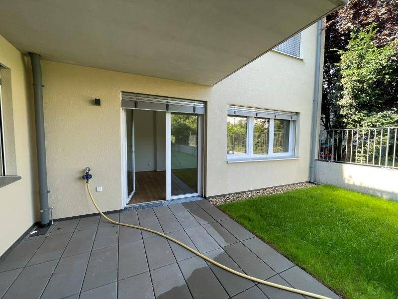 Geräumige Terrasse mit Fliesenboden und angrenzender Rasenfläche, ideal für entspannte Stunden im Freien.