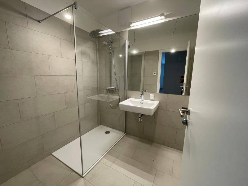 Modernes Badezimmer mit ebenerdiger Dusche, großformatigen Fliesen und elegantem Waschtisch.