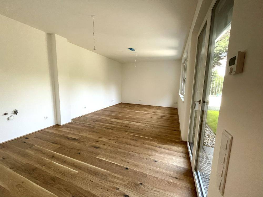 Geräumiges Wohnzimmer mit hellem Eichenparkett und großen Fenstern, die viel Tageslicht hereinlassen.