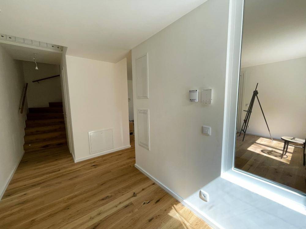 Heller Flurbereich mit Holzfußboden und Zugang zur Treppe, modern und einladend gestaltet.