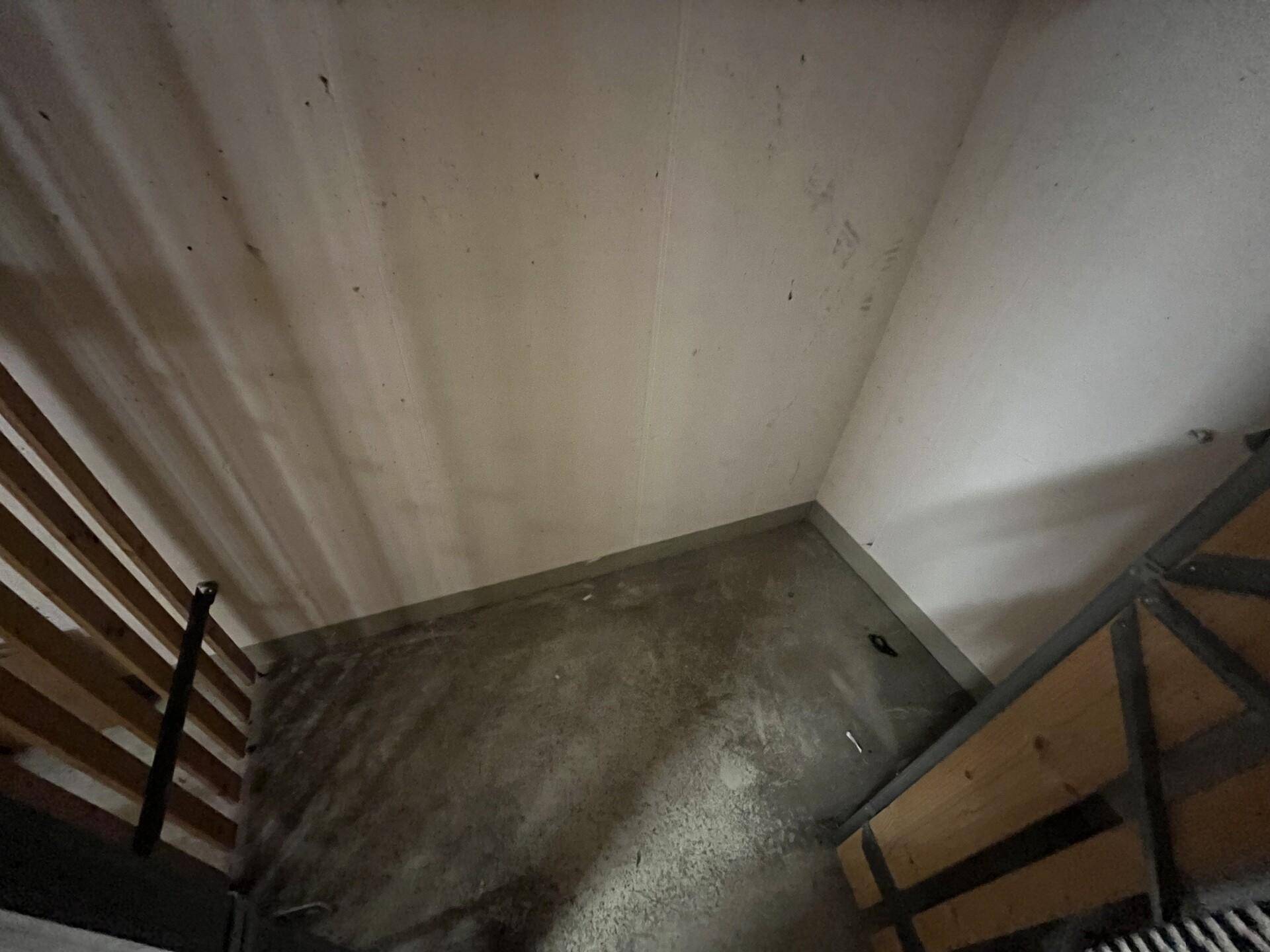Schlafzimmer mit zwei einfachen Bettgestellen und rohem Betonboden, die Wände sind hell und unaufgeräumt.