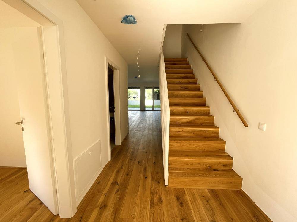Heller Flur mit Holztreppe und Eichenparkettboden, der zu den oberen Etagen führt.