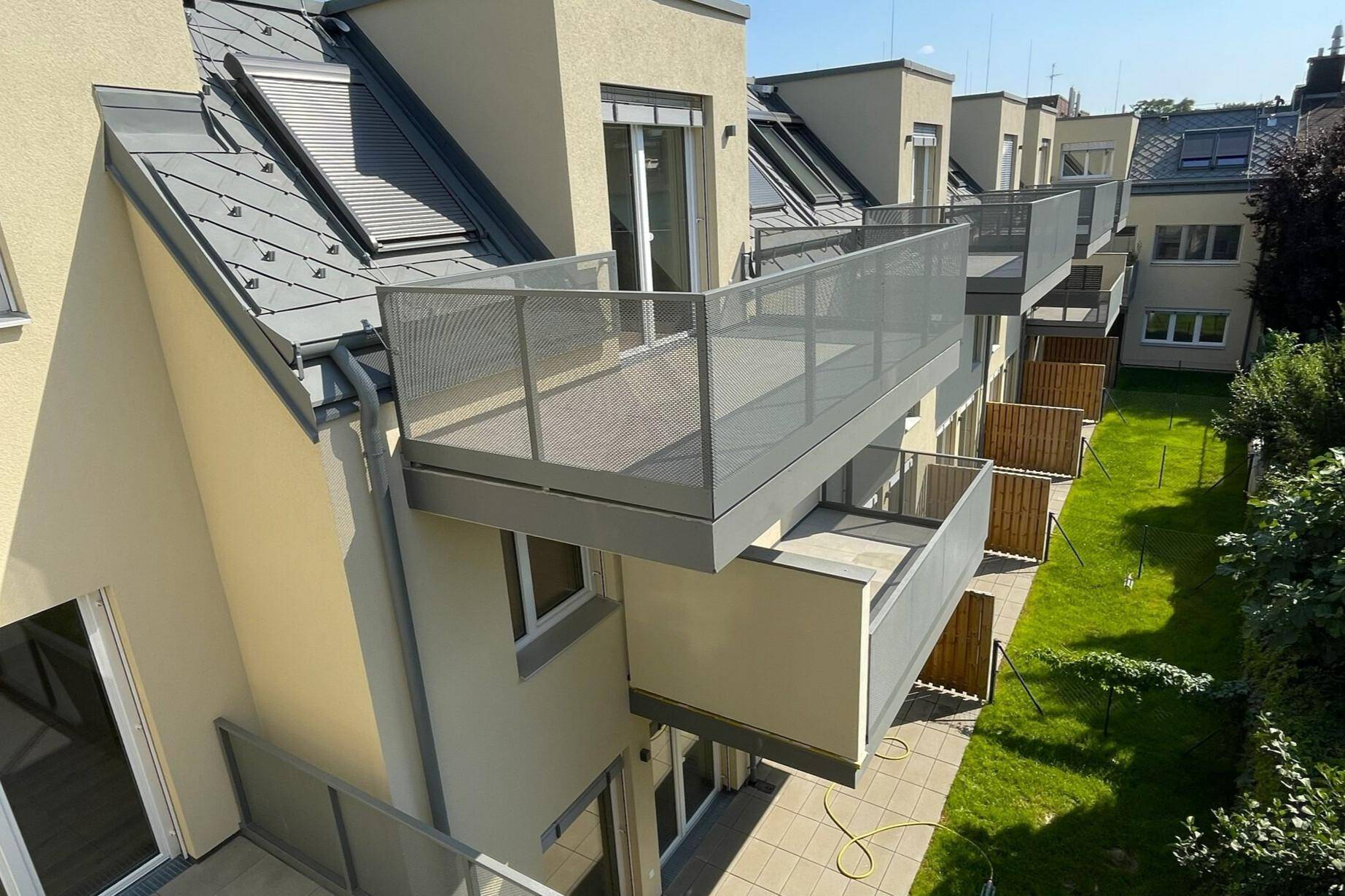 Mehrere moderne Balkone mit Glasgeländern an der Fassade eines Wohngebäudes.