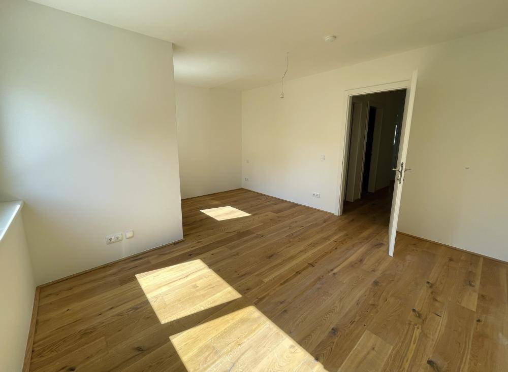 Großes, helles Zimmer mit Eichenparkettboden und viel Tageslicht durch die Fenster.