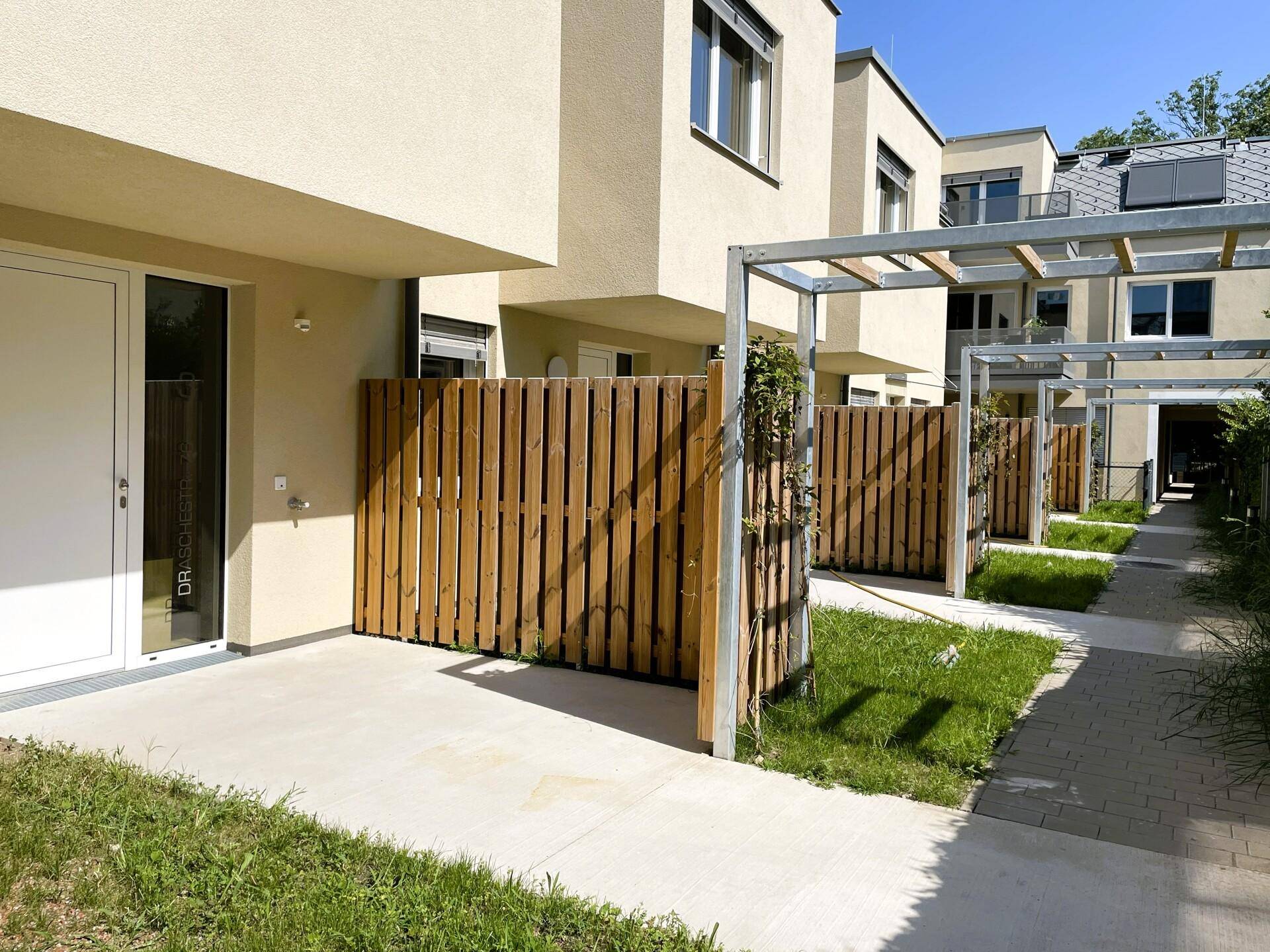 Moderne Reihenhäuser mit kleinen Vorgärten und Gehwegen in einer gepflegten Anlage.