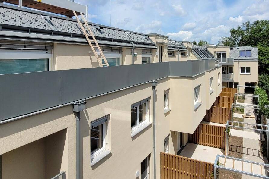 Ansicht der modernen Wohnanlage von oben mit Balkonen, Dachfenstern und privaten Gartenbereichen.