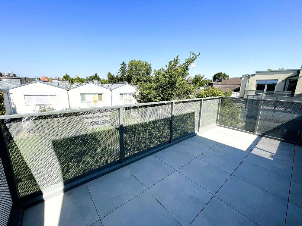 Weitläufiger Blick von der Dachterrasse auf grüne Bäume und die umliegende Wohnbebauung.
