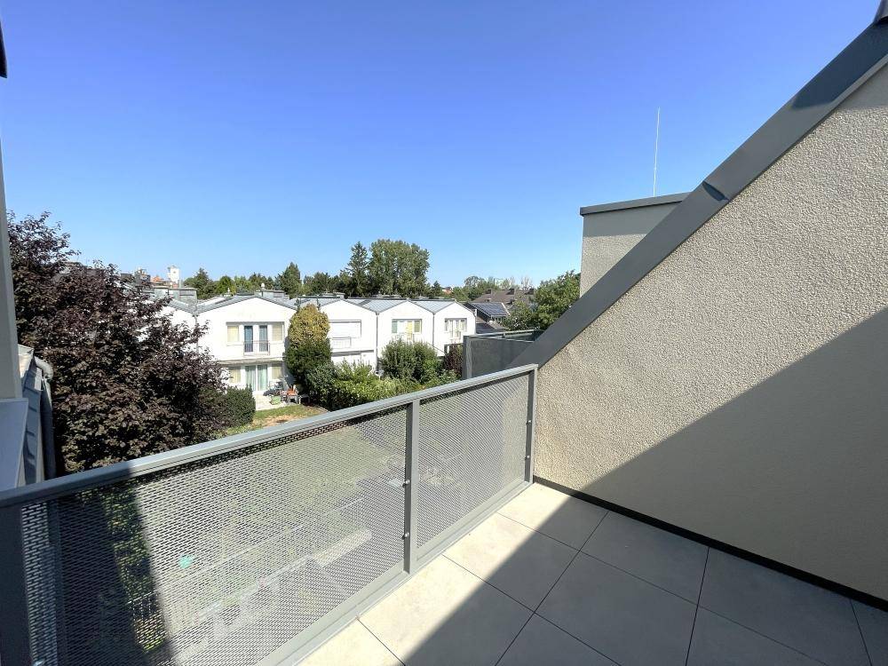 Balkon mit weitem Blick über die grüne Umgebung und die umliegenden Häuser.
