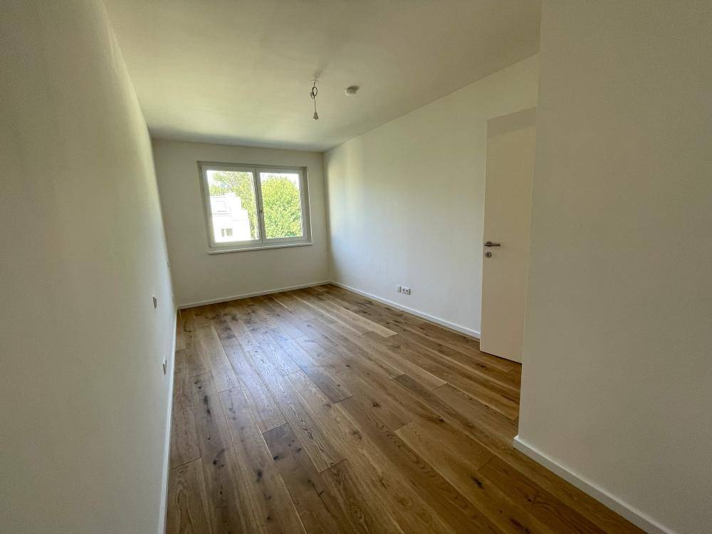 Helles Zimmer mit Holzparkett und Fenster, ideal als Schlaf- oder Arbeitszimmer nutzbar.