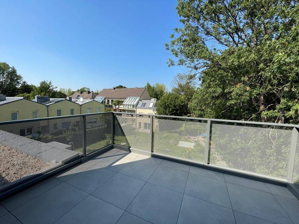 Balkon mit Fliesenboden und Metallgeländer bietet weiten Blick auf die Nachbarschaft und Bäume.