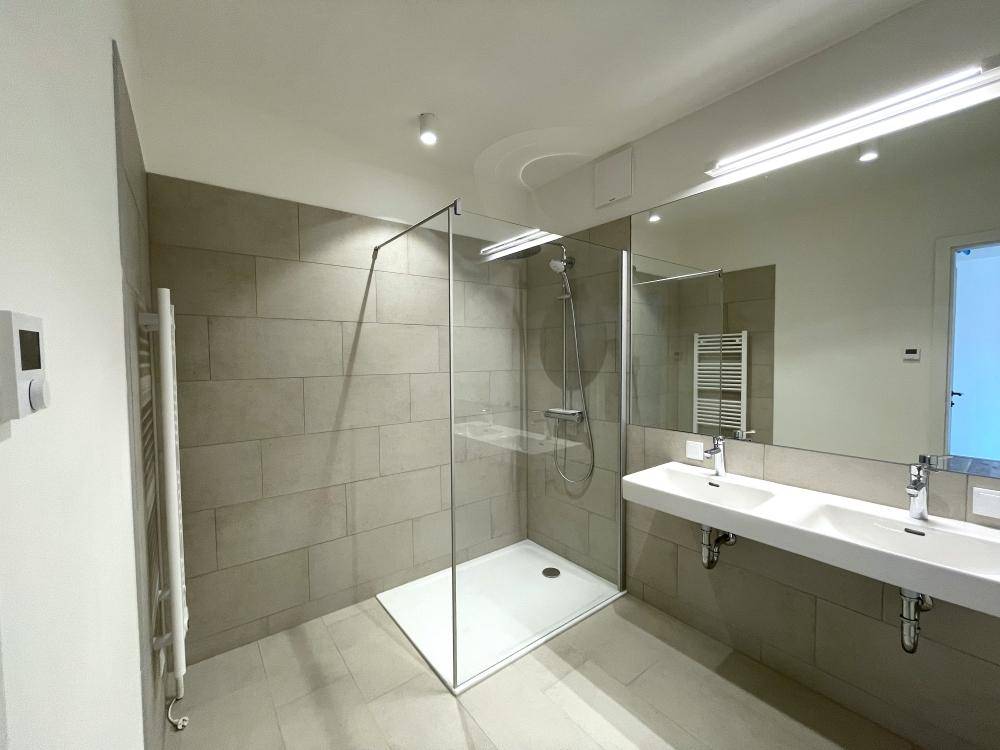 Modernes Badezimmer mit Doppelwaschbecken, großer begehbarer Dusche und beheiztem Handtuchhalter.