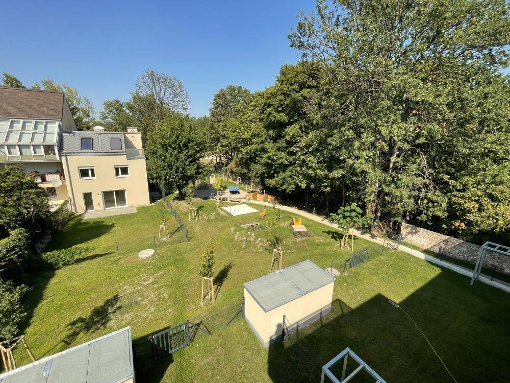 Weitläufiger Gemeinschaftsgarten mit Spielplatz und viel Grünfläche für Kinder zum Spielen.