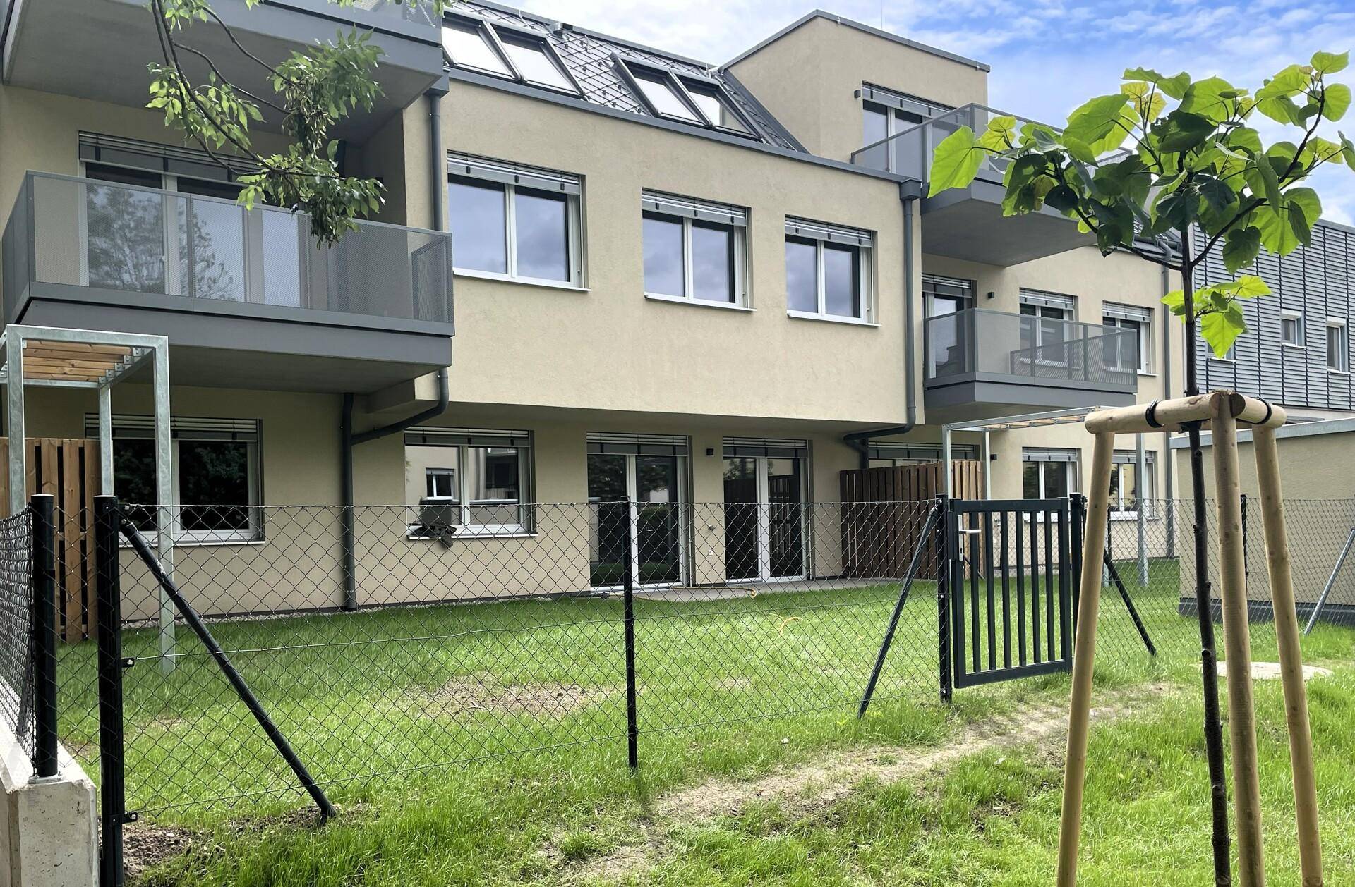 Moderne Neubau-Fassade mit privaten Gärten im Erdgeschoss und Balkonen in den oberen Etagen.