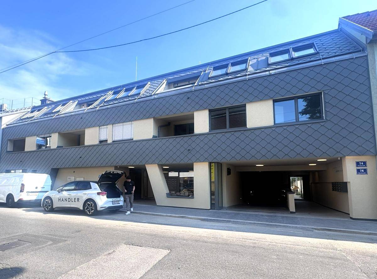 Moderne Straßenfassade des Gebäudes mit Parkplätzen und Schrägdach.