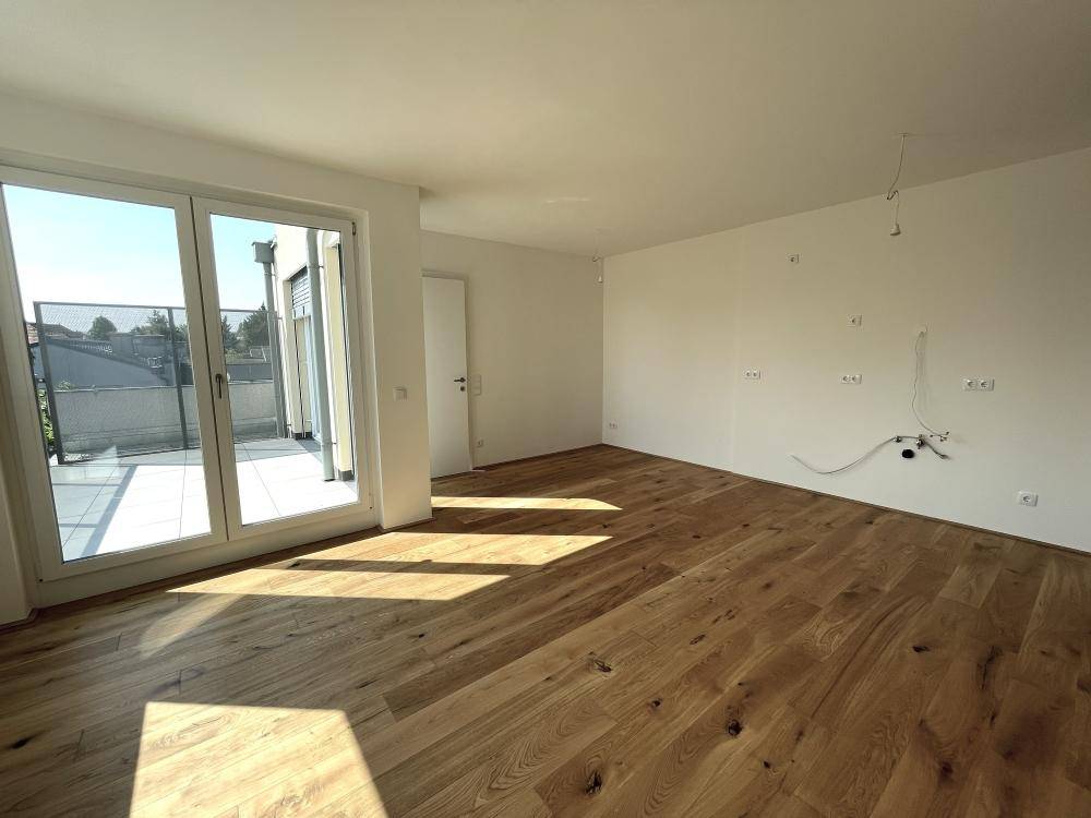 Helles Wohnzimmer mit neuem Holzboden und großen Fenstern, die viel Tageslicht hereinlassen.