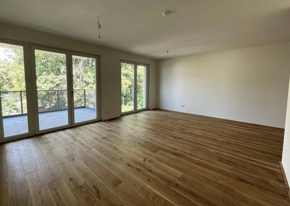 Großzügiger, heller Wohnraum mit Eichenparkett und bodentiefen Fenstern zum Balkon.