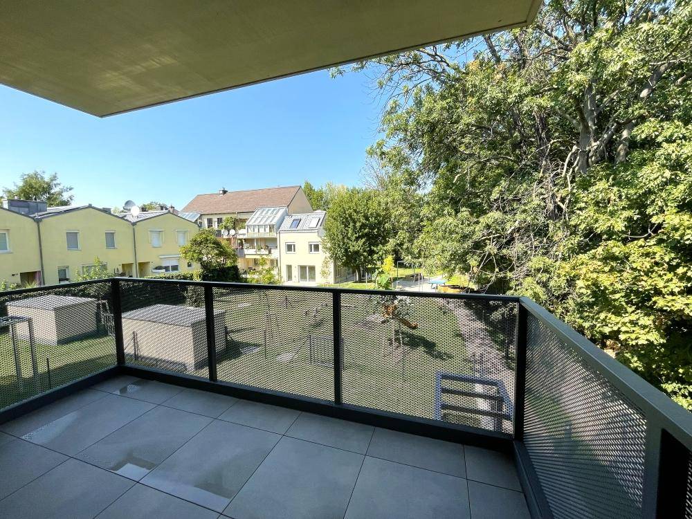 Geräumiger Balkon mit Fliesenboden und Ausblick auf die umliegenden Gebäude und Grünflächen.