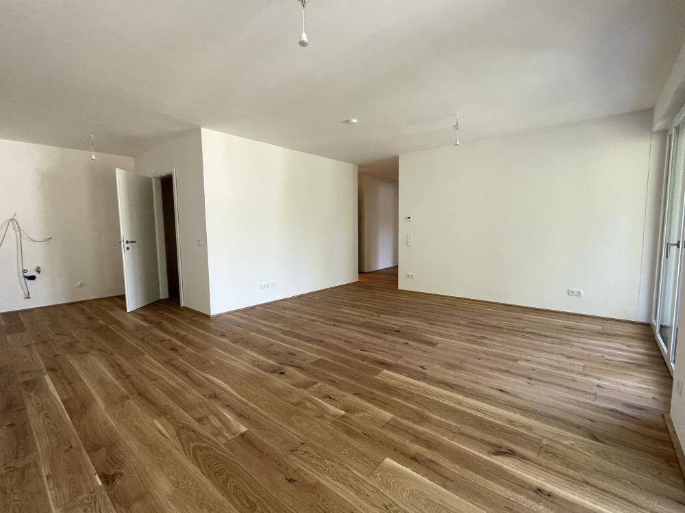 Weitläufiger, heller Raum mit elegantem Holzparkett und weißen Wänden, bereit zur individuellen Gestaltung.