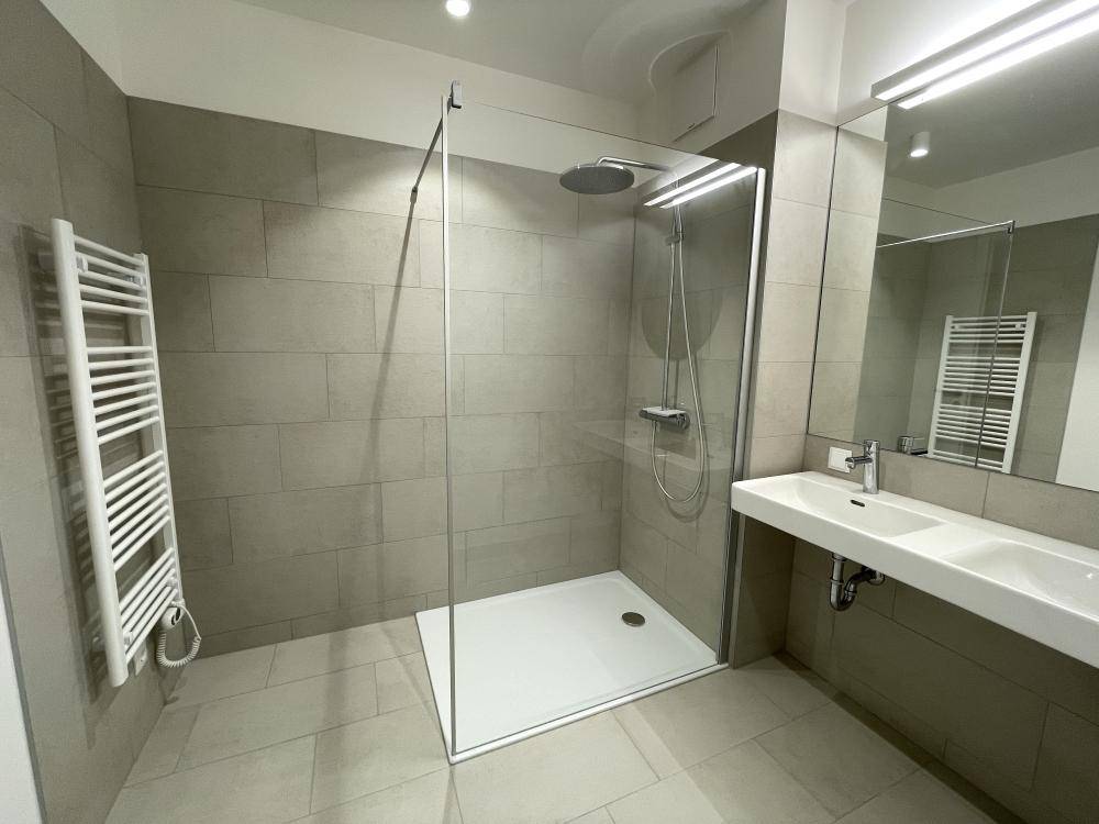Modernes Badezimmer mit großer begehbarer Dusche, Doppelwaschbecken und beheiztem Handtuchhalter.