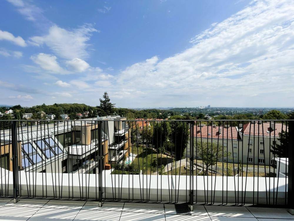 Weitblick von der Terrasse über moderne Gebäude, Grünflächen und die Stadt.