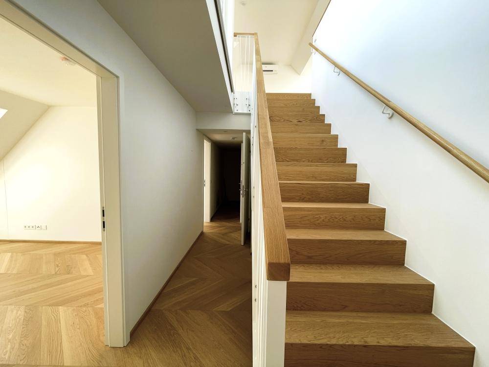 Eleganter Holztreppenaufgang und Flur mit Fischgrätparkett in modernem Design.