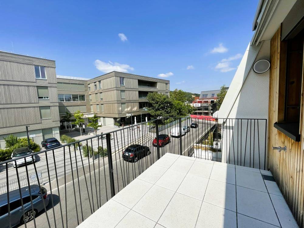 Sonniger Balkon mit Weitblick über die Wohngegend und die modernen Gebäude unter blauem Himmel.