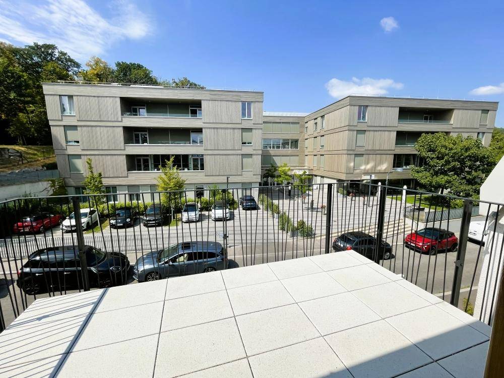 Balkon mit Weitblick auf die moderne Wohnanlage und die gepflegte Umgebung mit Parkplätzen.