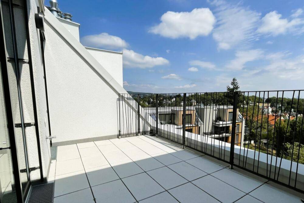 Sonniger Balkon mit moderner Brüstung und weitem Blick über die Dächer und Bäume.