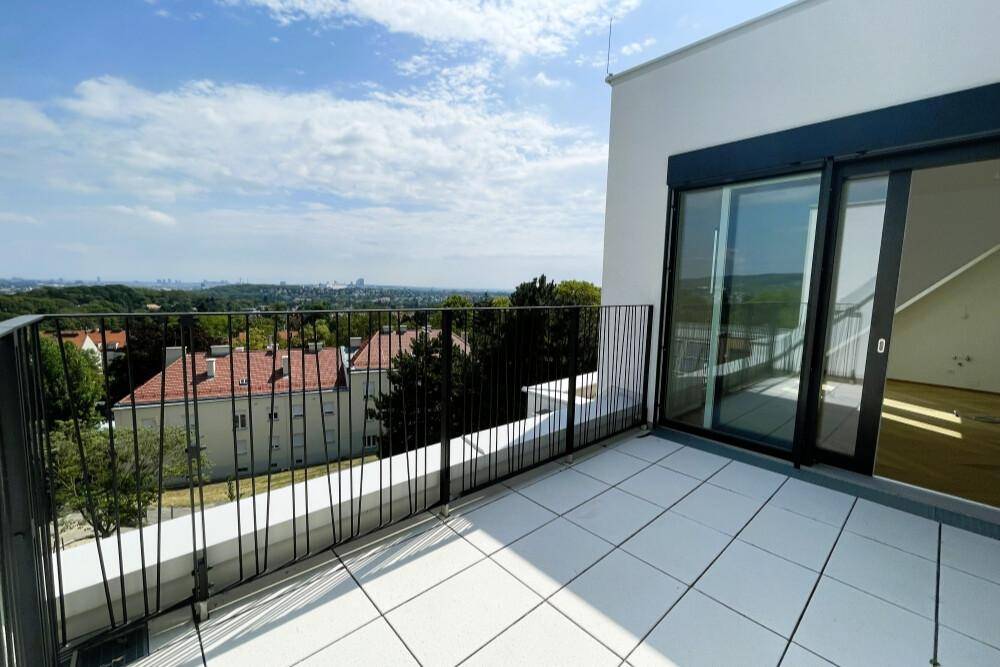 Heller Balkon mit Schiebetüren und Panoramablick auf die umliegende Landschaft und Stadt.