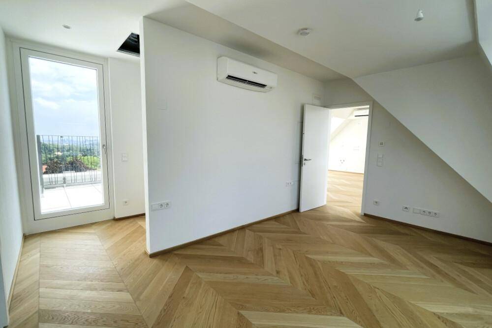 Geräumiges Zimmer mit Fischgrätparkett, Klimaanlage und Zugang zu einem französischen Balkon.
