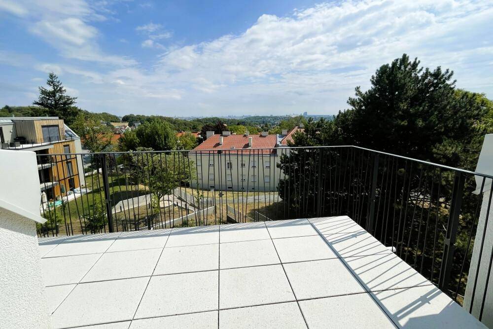 Geräumiger Balkon mit Fliesenboden und weitem Blick über die Stadt und grüne Umgebung.