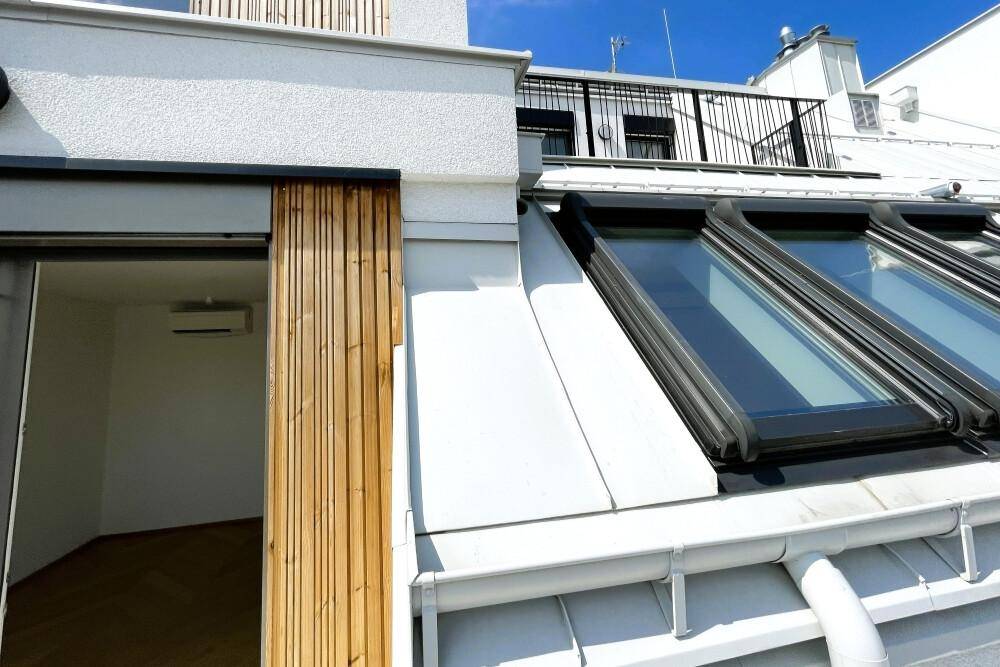 Dachansicht mit modernen Dachfenstern und Zugang zu einem Balkon von einem Zimmer.