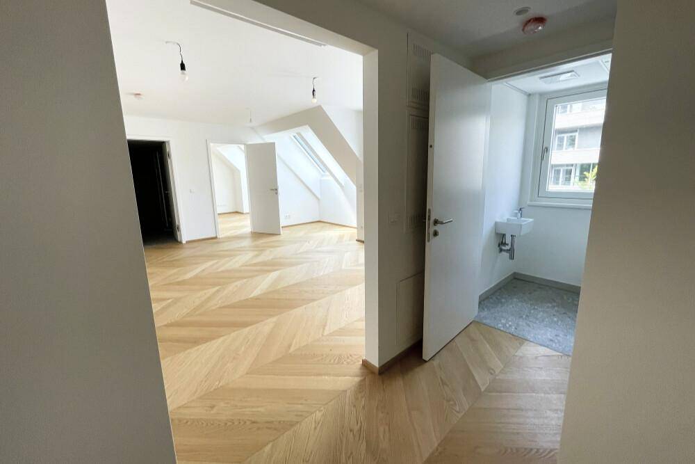 Geräumiger Flur mit elegantem Fischgrätparkett, der zu verschiedenen Zimmern und einem Gäste-WC führt.