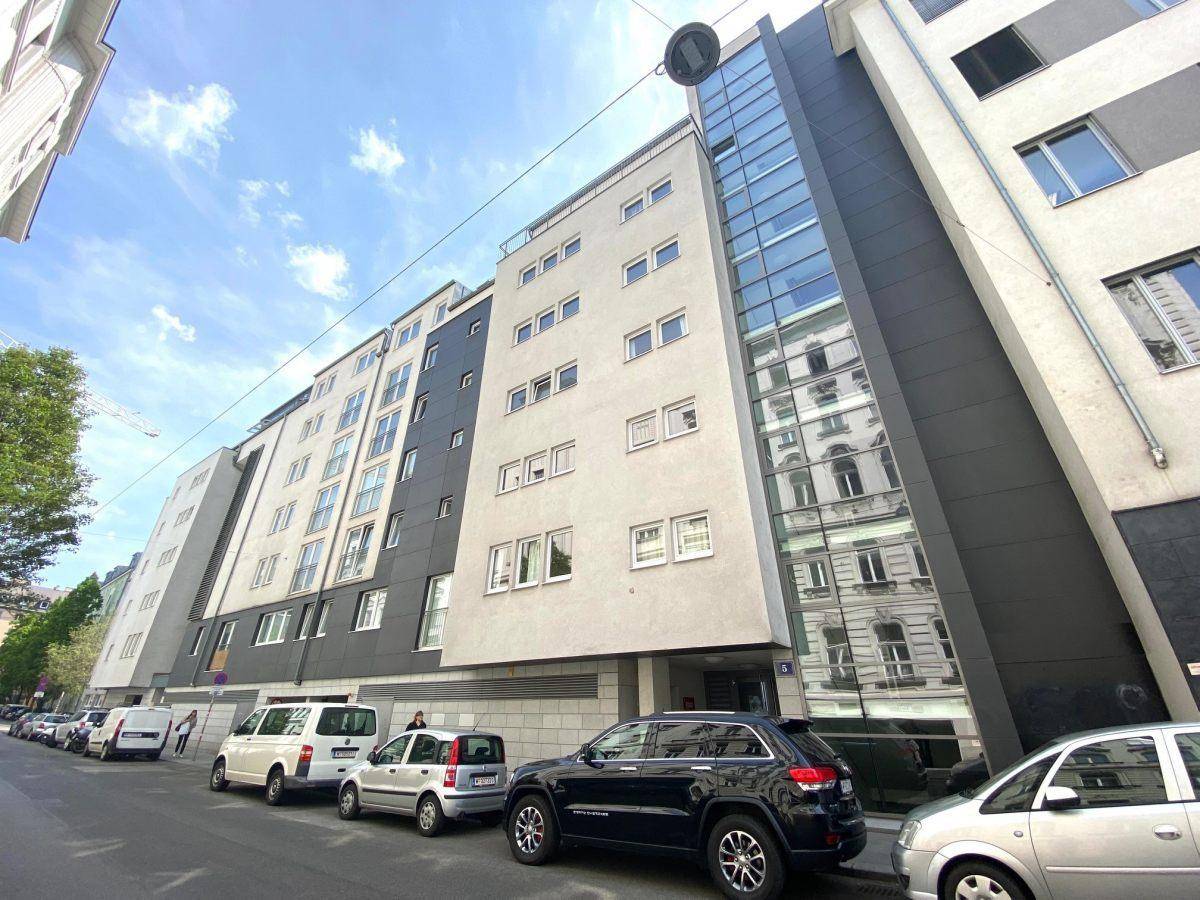 Moderne Gebäudefassade mit großen Glasflächen und urbaner Umgebung.